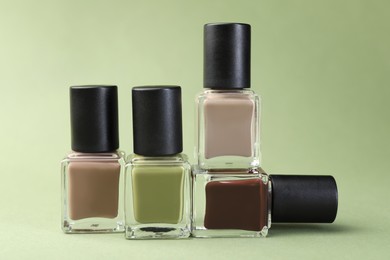 Photo of Nail polishes in bottles on olive background