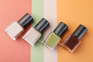 Photo of Nail polishes in bottles on color background, flat lay