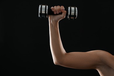 Photo of Woman exercising with dumbbell on black background, closeup. Space for text