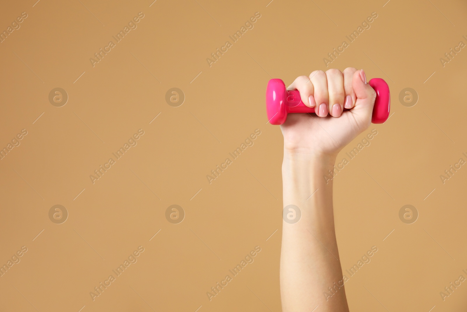 Photo of Woman exercising with dumbbell on beige background, closeup. Space for text