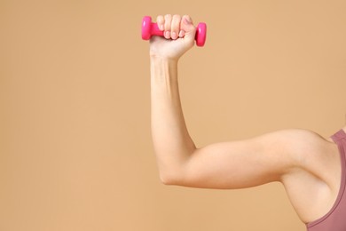 Photo of Woman exercising with dumbbell on beige background, closeup. Space for text