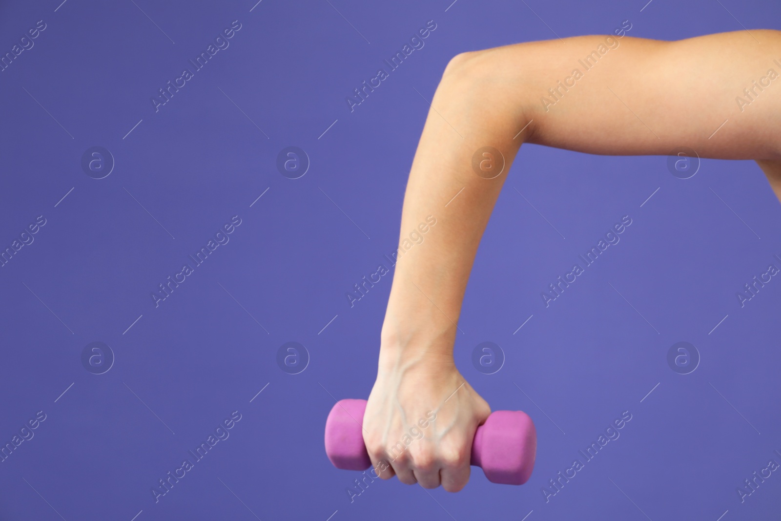 Photo of Woman exercising with dumbbell on purple background, closeup. Space for text