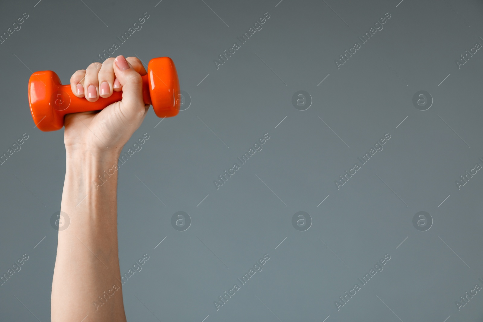 Photo of Woman exercising with dumbbell on light grey background, closeup. Space for text