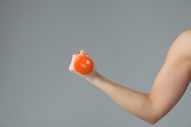 Photo of Woman exercising with dumbbell on light grey background, closeup. Space for text