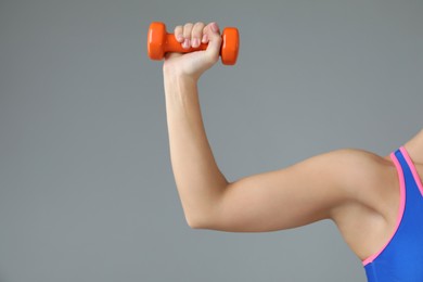 Photo of Woman exercising with dumbbell on light grey background, closeup. Space for text