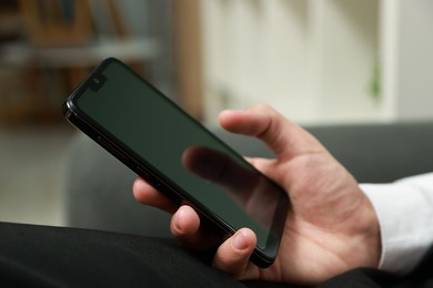 Photo of Man using smartphone with blank screen indoors, closeup