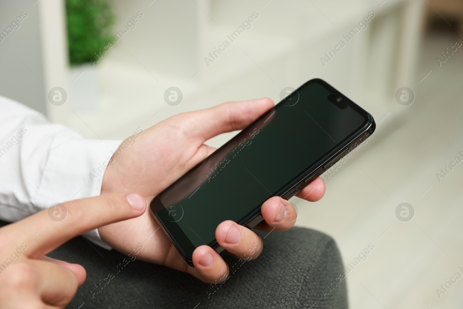 Photo of Man using smartphone with blank screen indoors, closeup