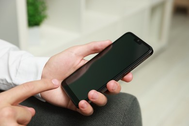 Photo of Man using smartphone with blank screen indoors, closeup