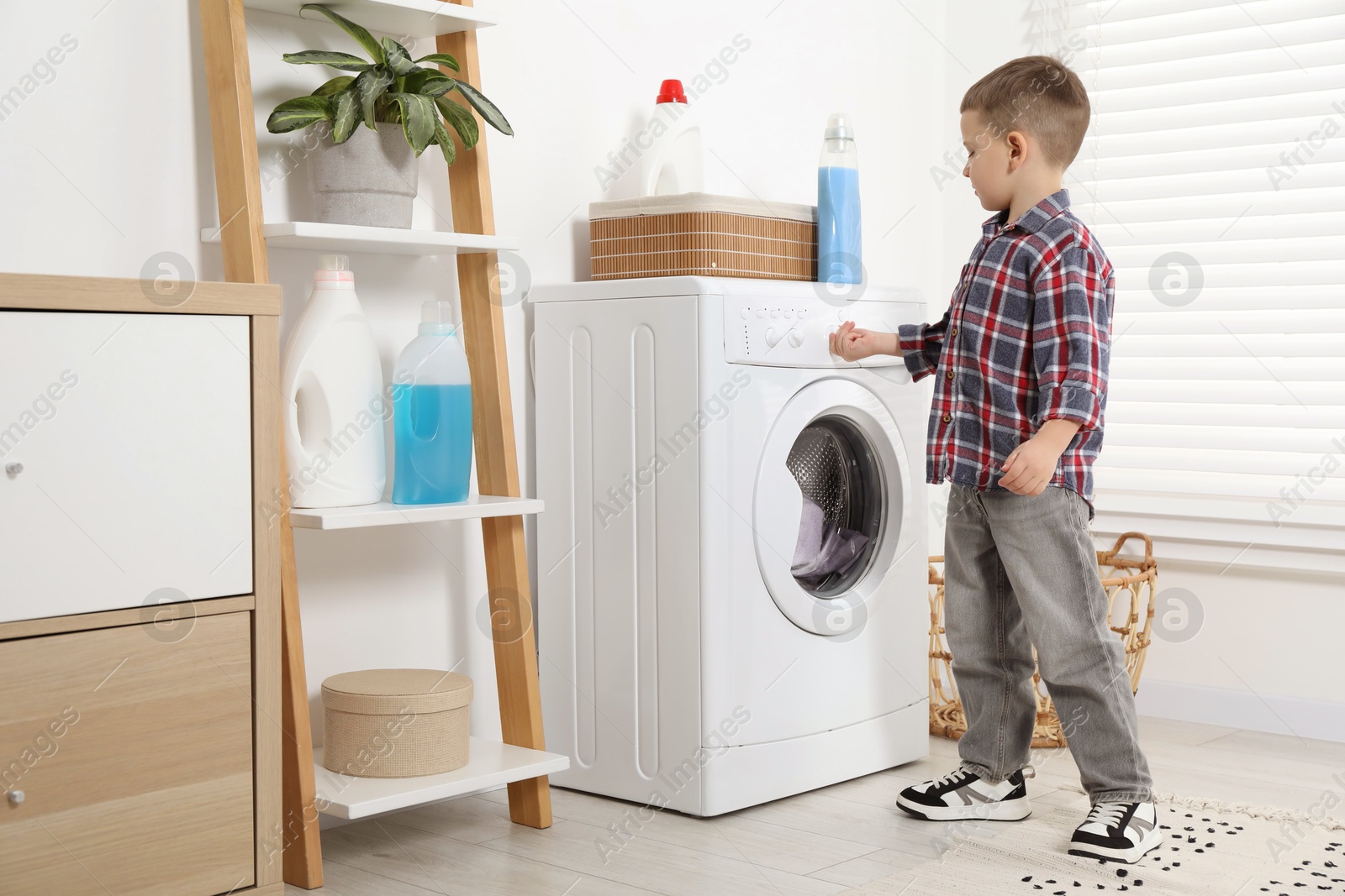 Photo of Little helper. Cute boy doing laundry at home