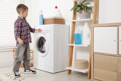 Photo of Little helper. Cute boy doing laundry at home