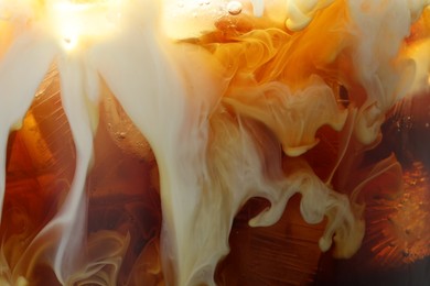 Photo of Refreshing coffee with ice and milk as background, closeup