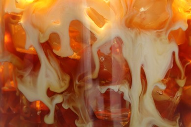 Photo of Refreshing coffee with ice and milk as background, closeup