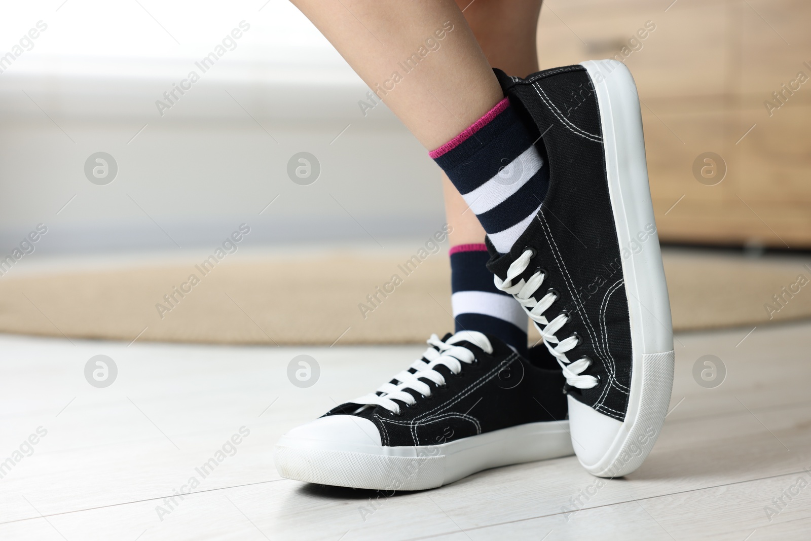 Photo of Child wearing oversized sneakers indoors, closeup. Space for text