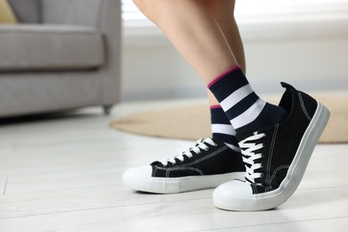 Photo of Child wearing oversized sneakers indoors, closeup. Space for text