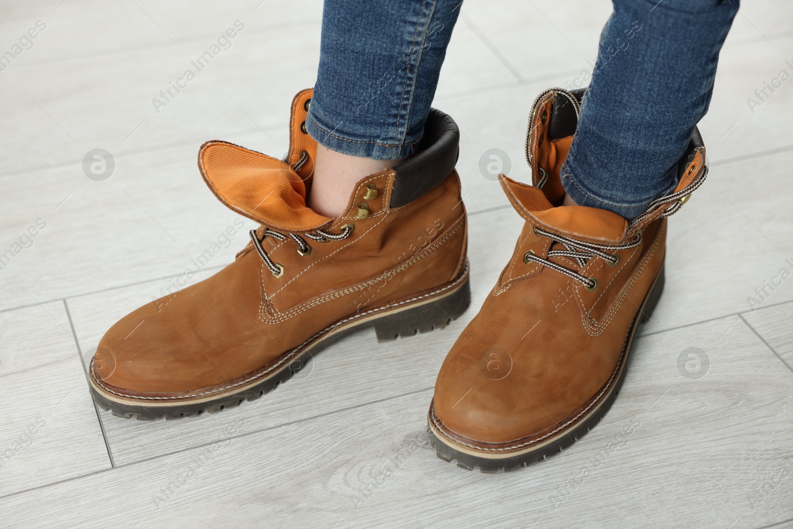 Photo of Child wearing oversized brown boots indoors, closeup