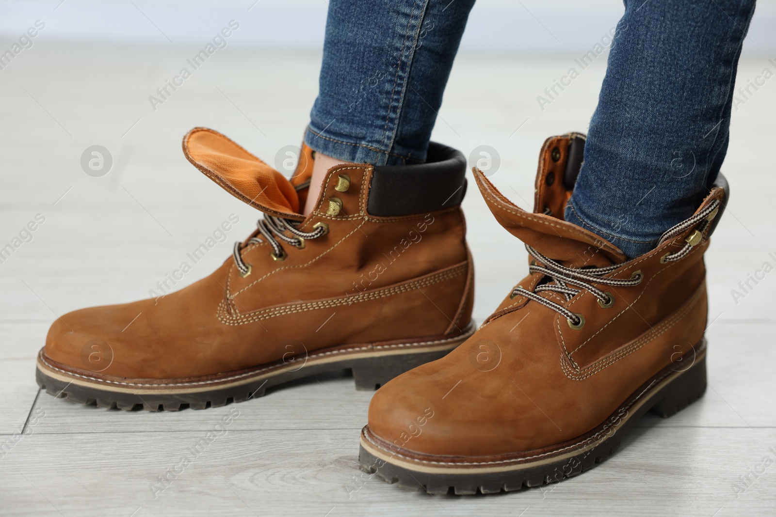 Photo of Child wearing oversized brown boots indoors, closeup