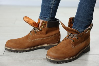 Photo of Child wearing oversized brown boots indoors, closeup