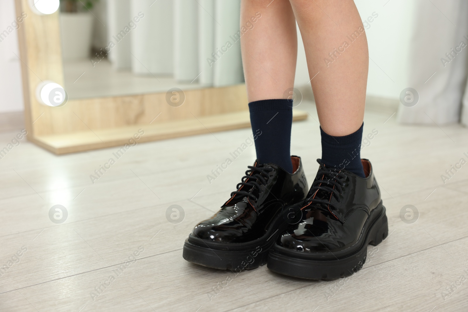 Photo of Child wearing oversized shoes indoors, closeup. Space for text