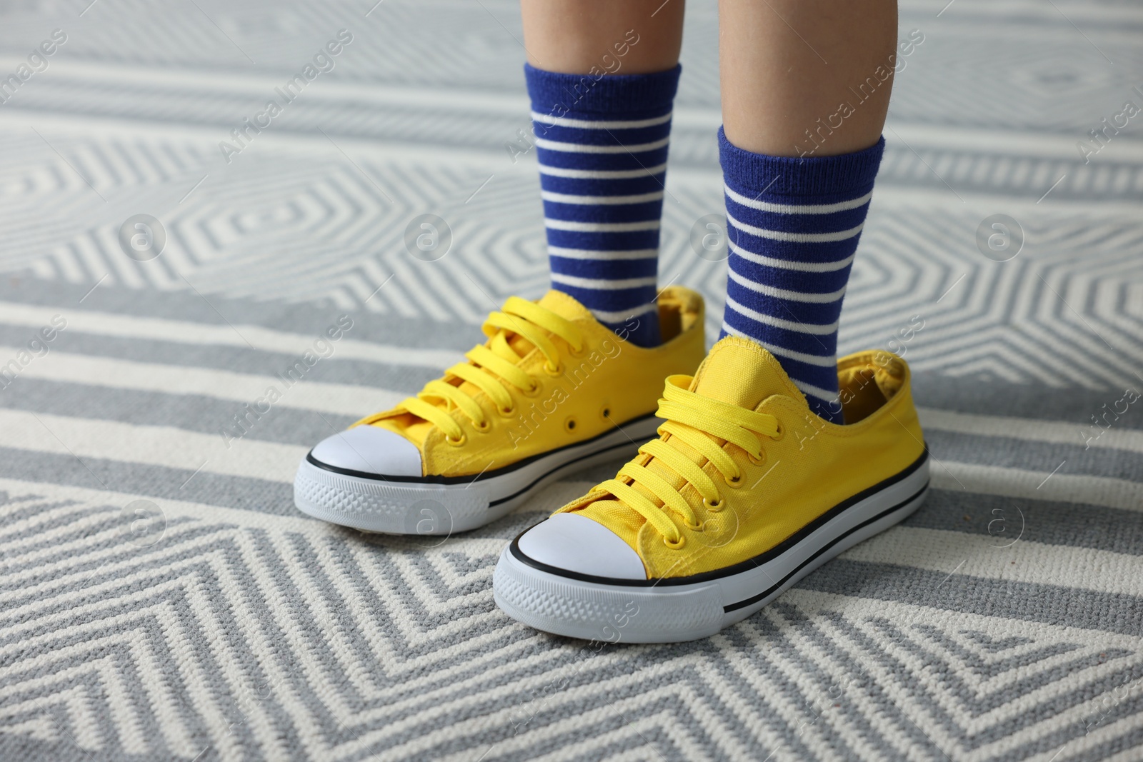 Photo of Child wearing oversized yellow sneakers indoors, closeup