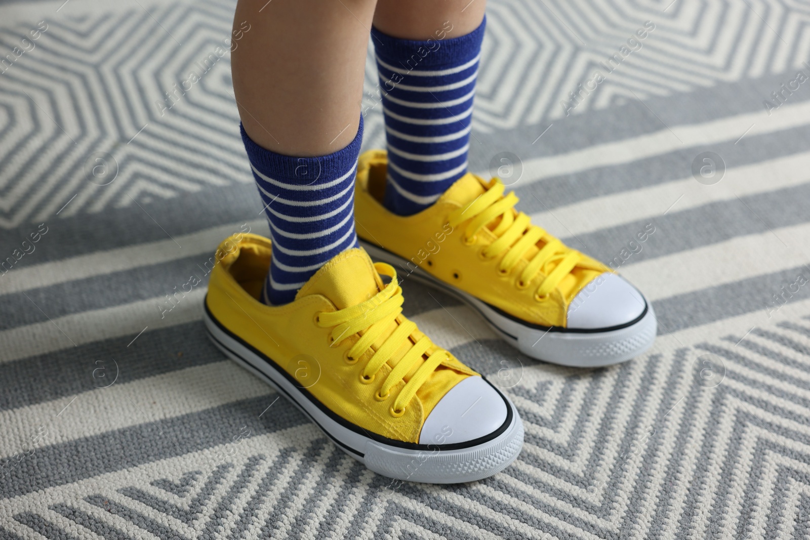 Photo of Child wearing oversized yellow sneakers indoors, closeup