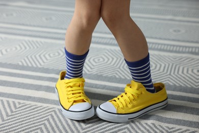 Photo of Child wearing oversized yellow sneakers indoors, closeup