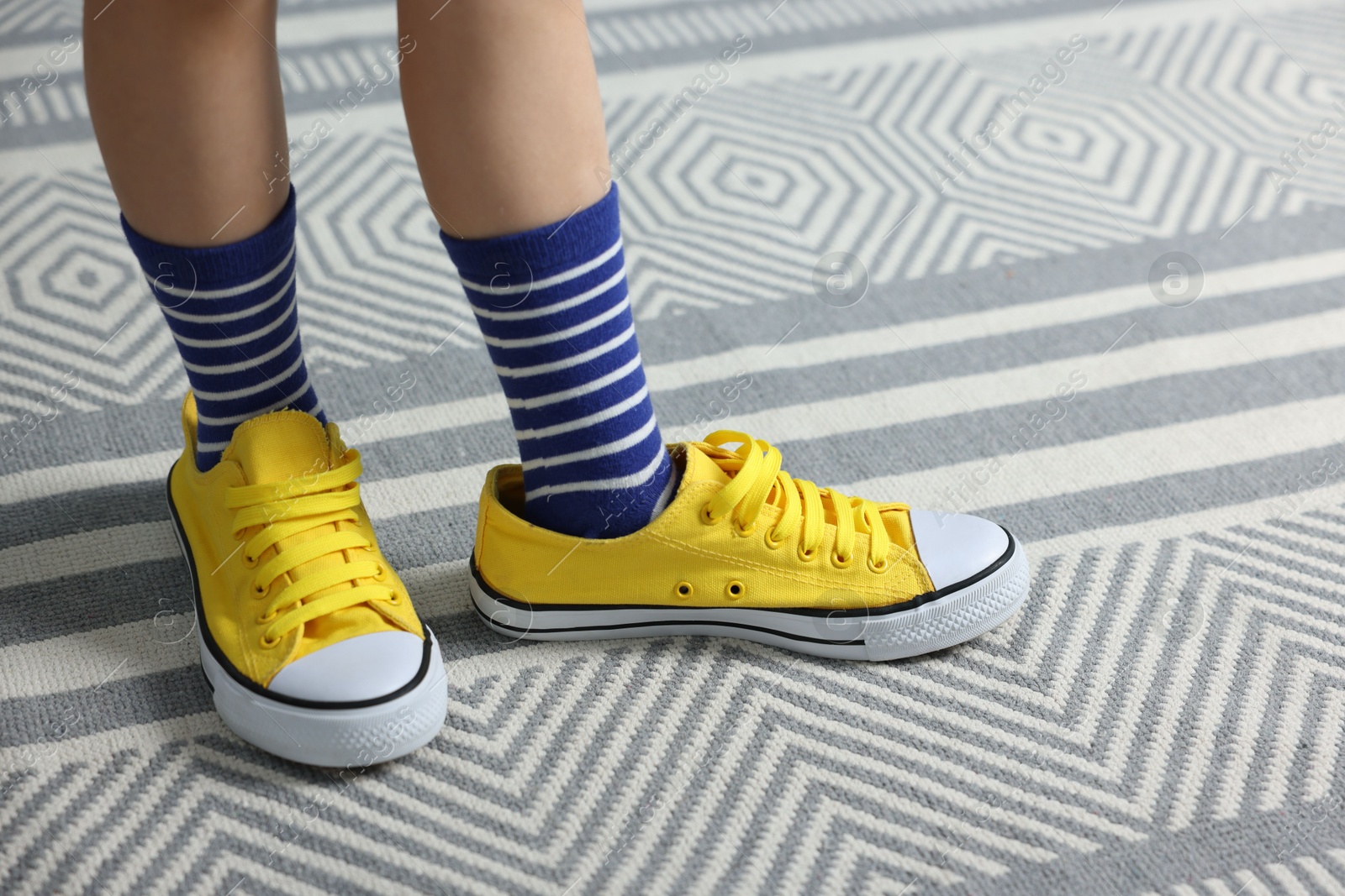 Photo of Child wearing oversized yellow sneakers indoors, closeup