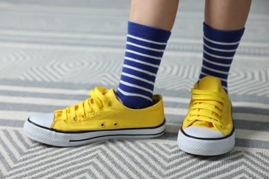 Photo of Child wearing oversized yellow sneakers indoors, closeup