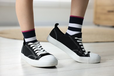 Photo of Child wearing oversized black sneakers indoors, closeup