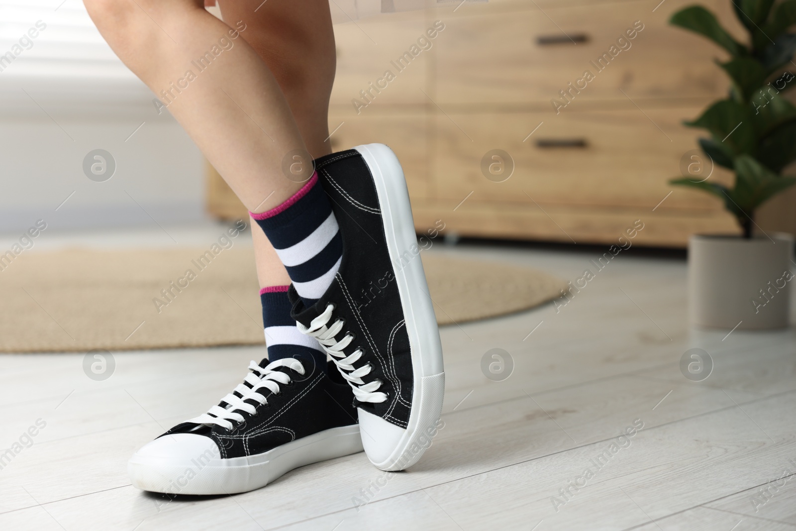 Photo of Child wearing oversized sneakers indoors, closeup. Space for text