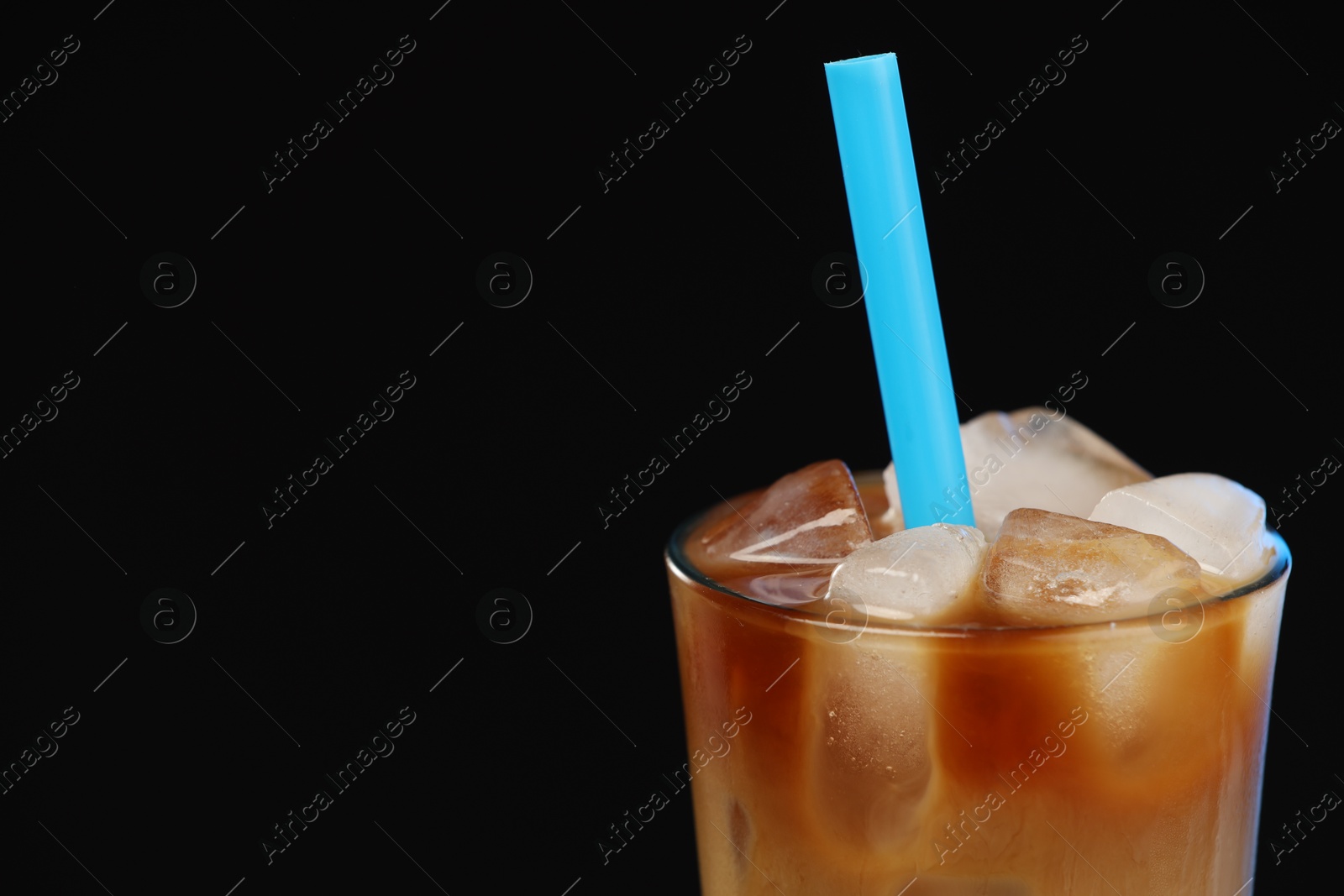 Photo of Refreshing iced coffee with milk in glass on black background, closeup. Space for text