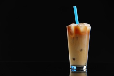 Photo of Refreshing iced coffee with milk in glass on black mirror surface. Space for text