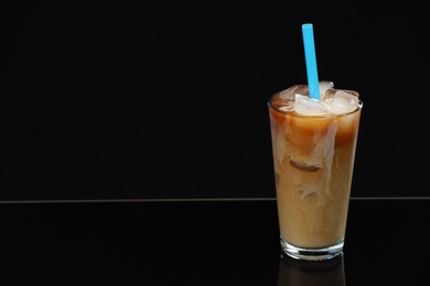 Photo of Refreshing iced coffee with milk in glass on black mirror surface. Space for text