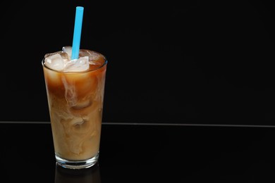 Photo of Refreshing iced coffee with milk in glass on black mirror surface. Space for text