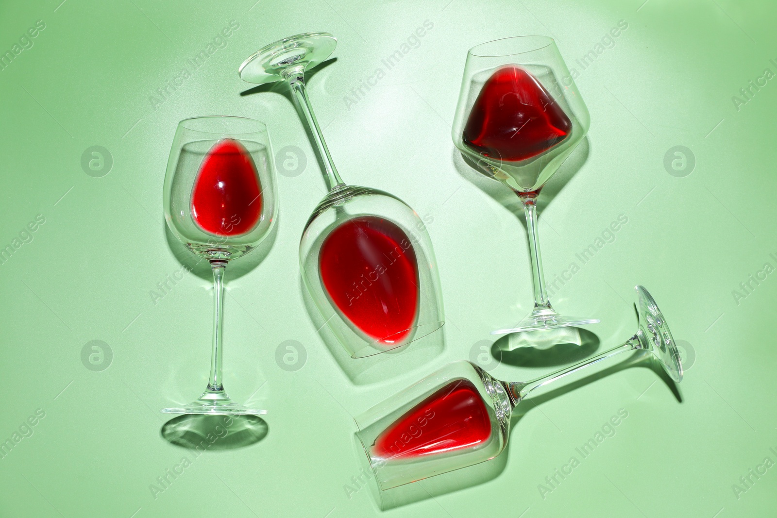 Photo of Glasses of red wine on light green background, flat lay