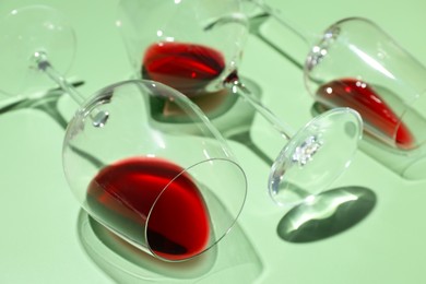 Photo of Glasses of red wine on light green background, closeup