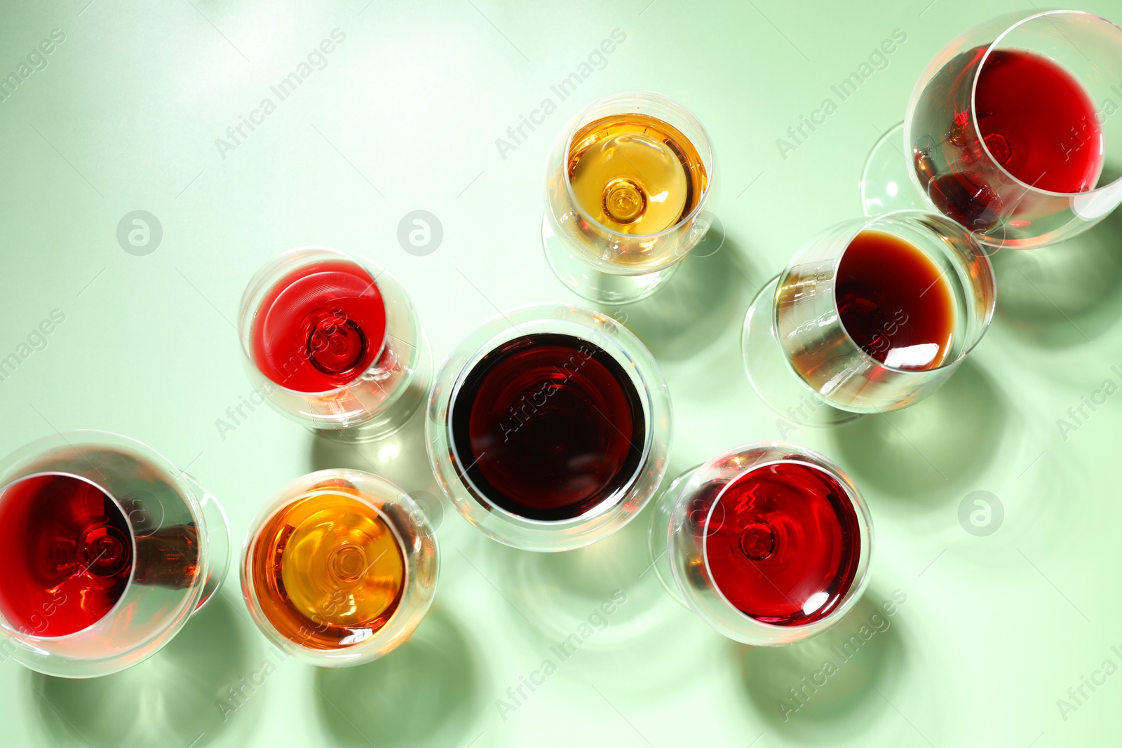 Photo of Glasses of different drinks on light green background, flat lay