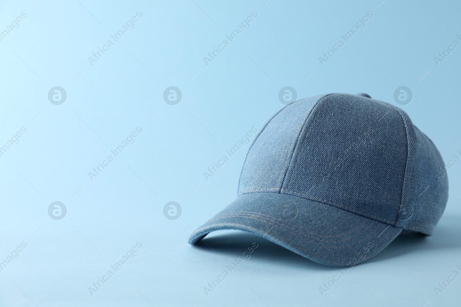 Photo of Stylish denim baseball cap on light blue background. Mockup for design