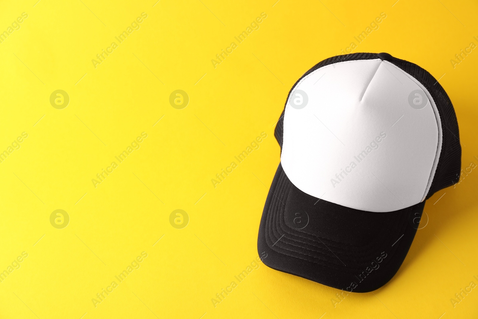 Photo of Stylish baseball cap on yellow background. Mockup for design