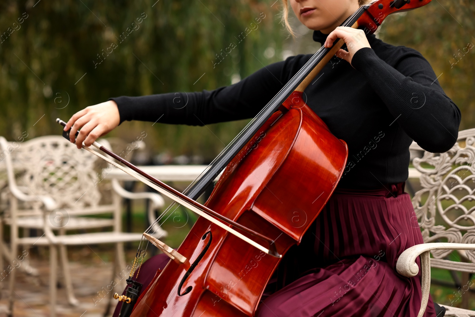 Photo of Young woman playing cello in park, closeup