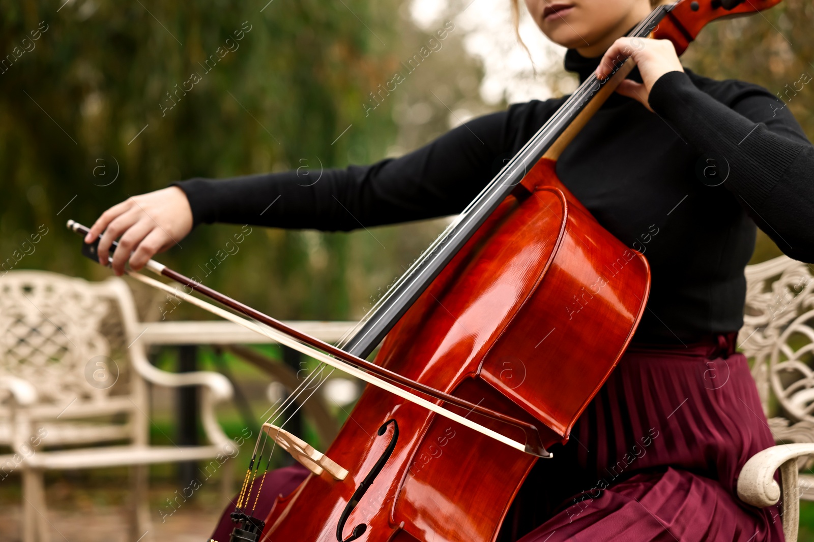 Photo of Young woman playing cello in park, closeup