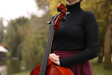 Photo of Woman with cello in park, closeup. Classic musical instrument