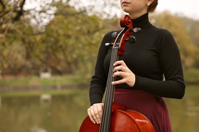 Photo of Young woman with cello in park, closeup. Space for text