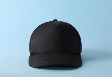 Photo of Stylish black baseball cap on light blue background. Mockup for design