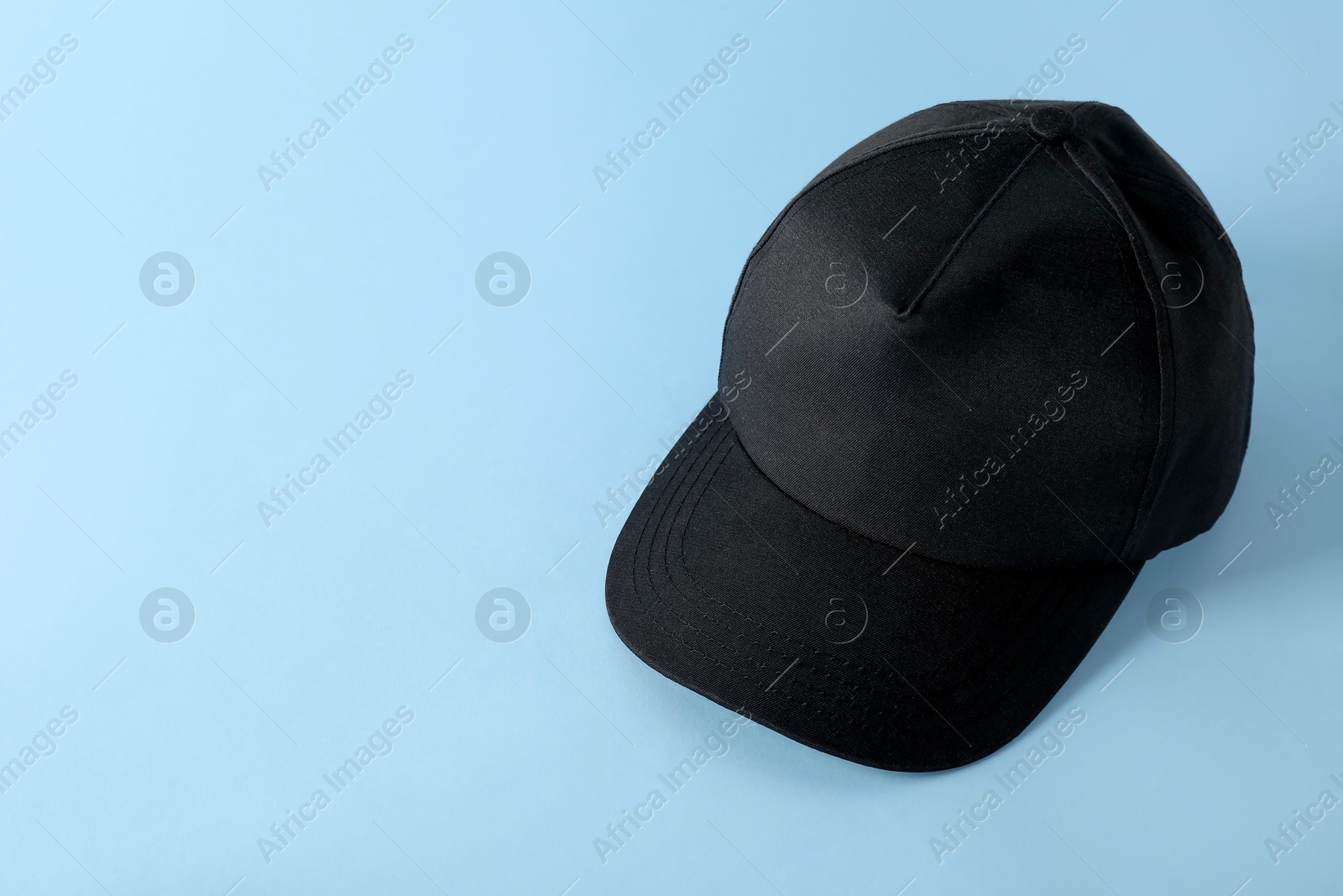 Photo of Stylish black baseball cap on light blue background. Mockup for design