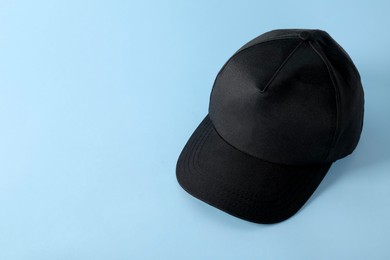 Photo of Stylish black baseball cap on light blue background. Mockup for design