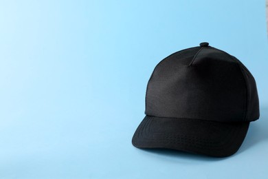 Photo of Stylish black baseball cap on light blue background. Mockup for design