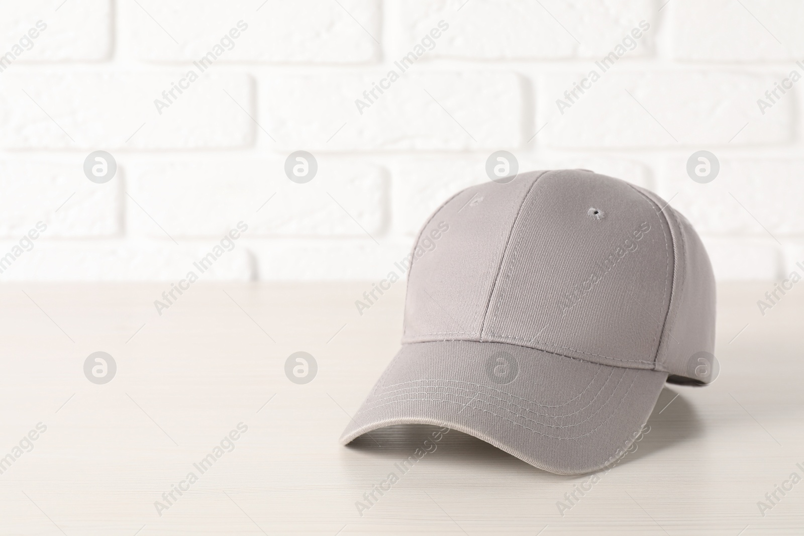 Photo of Stylish baseball cap on wooden table. Mockup for design