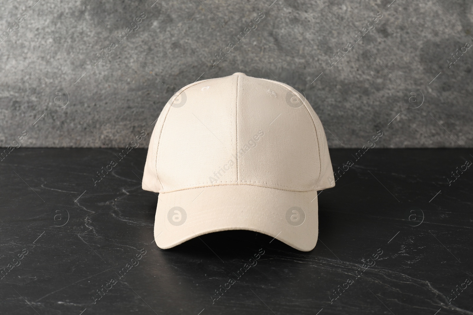 Photo of Stylish baseball cap on dark textured table. Mockup for design