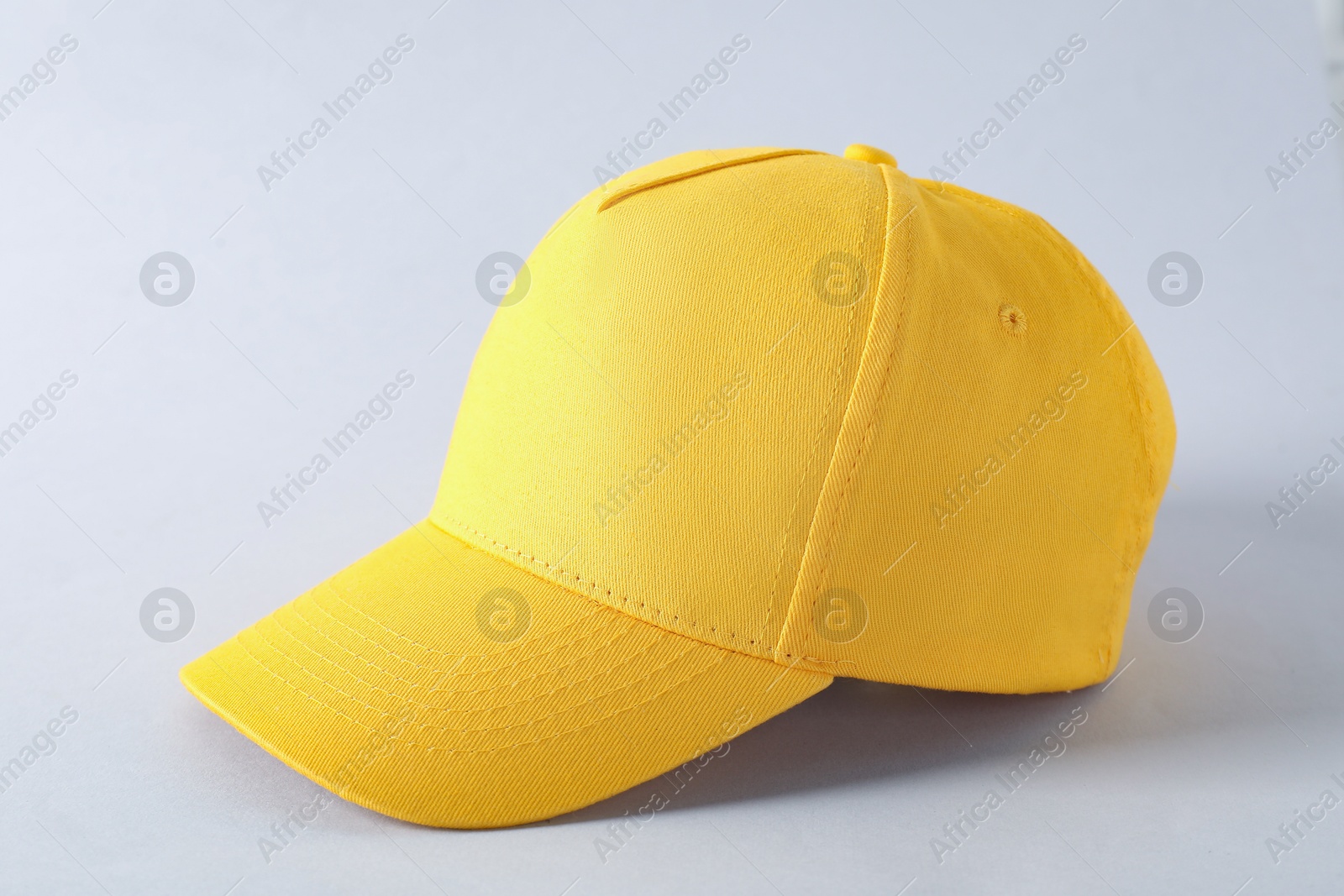 Photo of Stylish yellow baseball cap on light grey background, closeup. Mockup for design