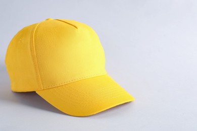 Photo of Stylish yellow baseball cap on light grey background, closeup. Mockup for design